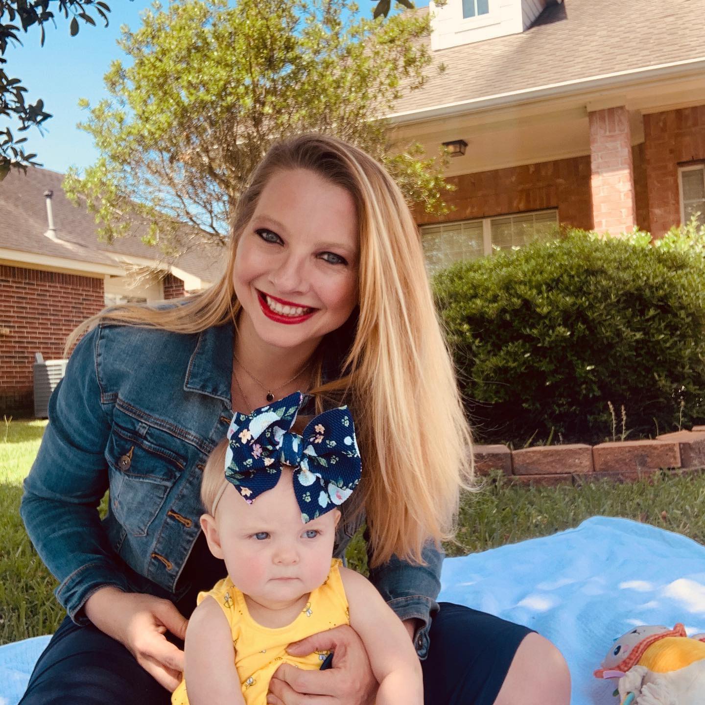 Candice Bingham, Director of Sales and Marketing, with her daughter sitting on a blanket outside a brick building.