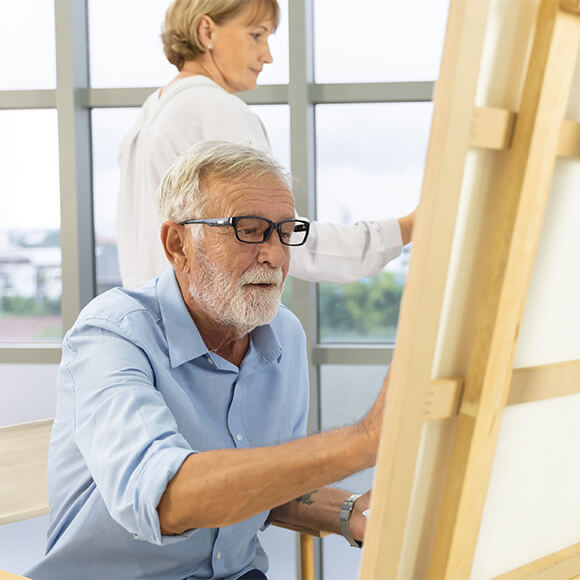 Older adults painting in a bright, art-filled common space.