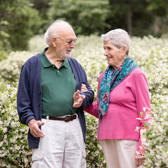 Elderly couple walking in a garden at a senior living community.