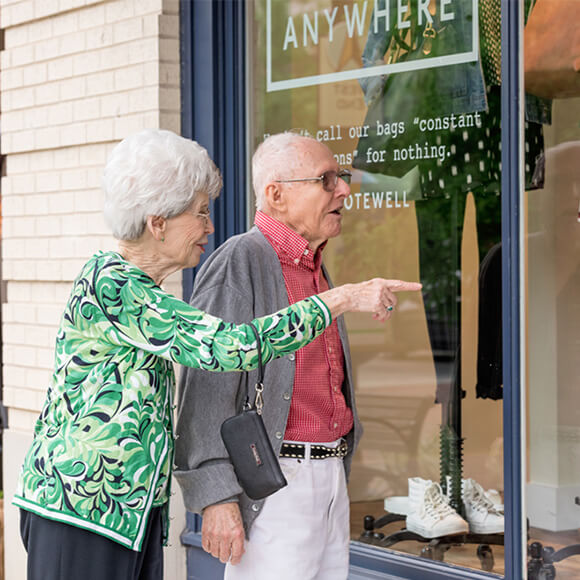 Older couple window shopping at a modern store in a senior living community.