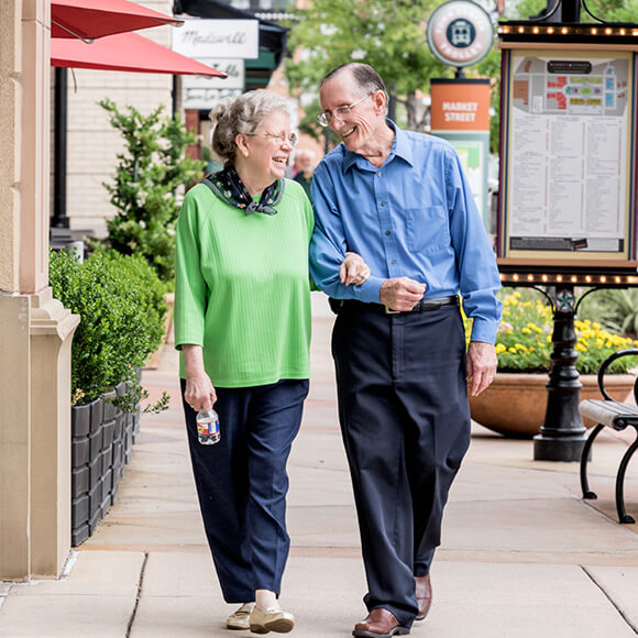 Elderly couple walking happily outside a senior living community.