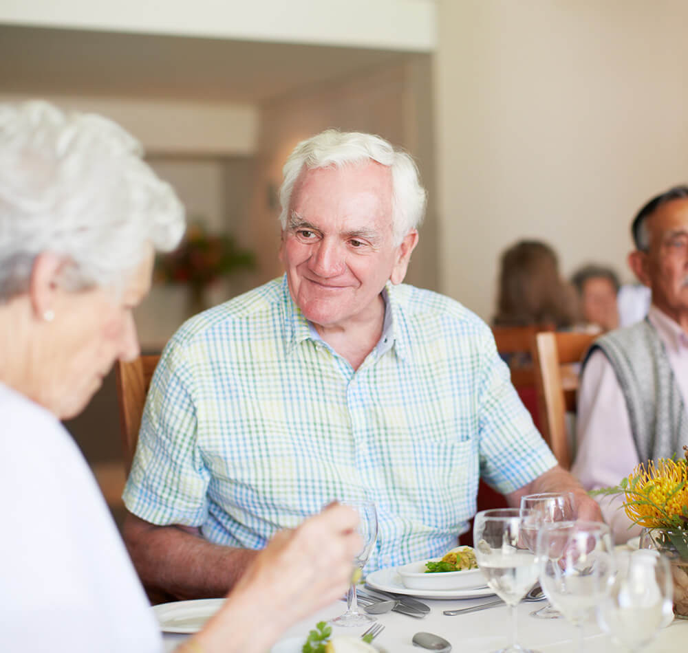 Senior residents enjoying a meal together in a dining area within the community.