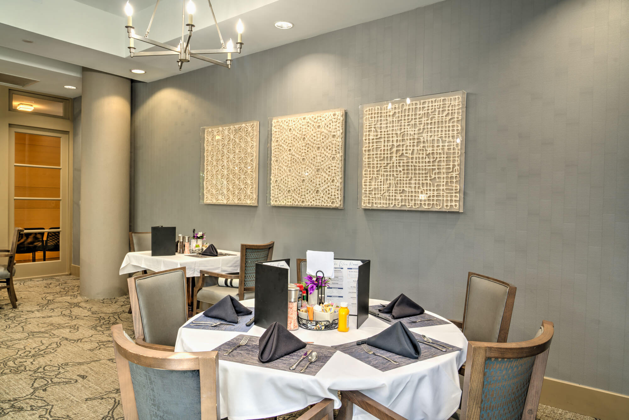 Elegant dining area with art on walls, set for a meal in a community unit.