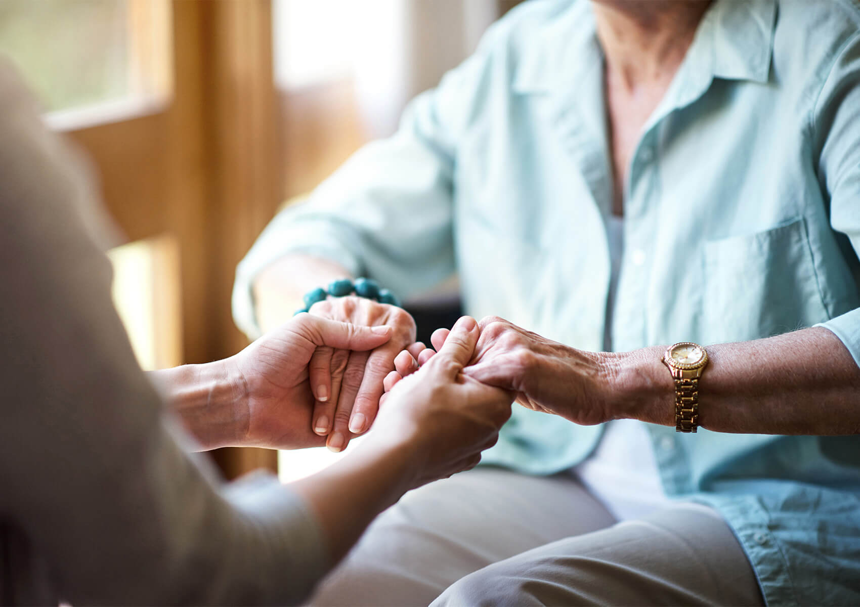 Caring health partner holding senior's hands.