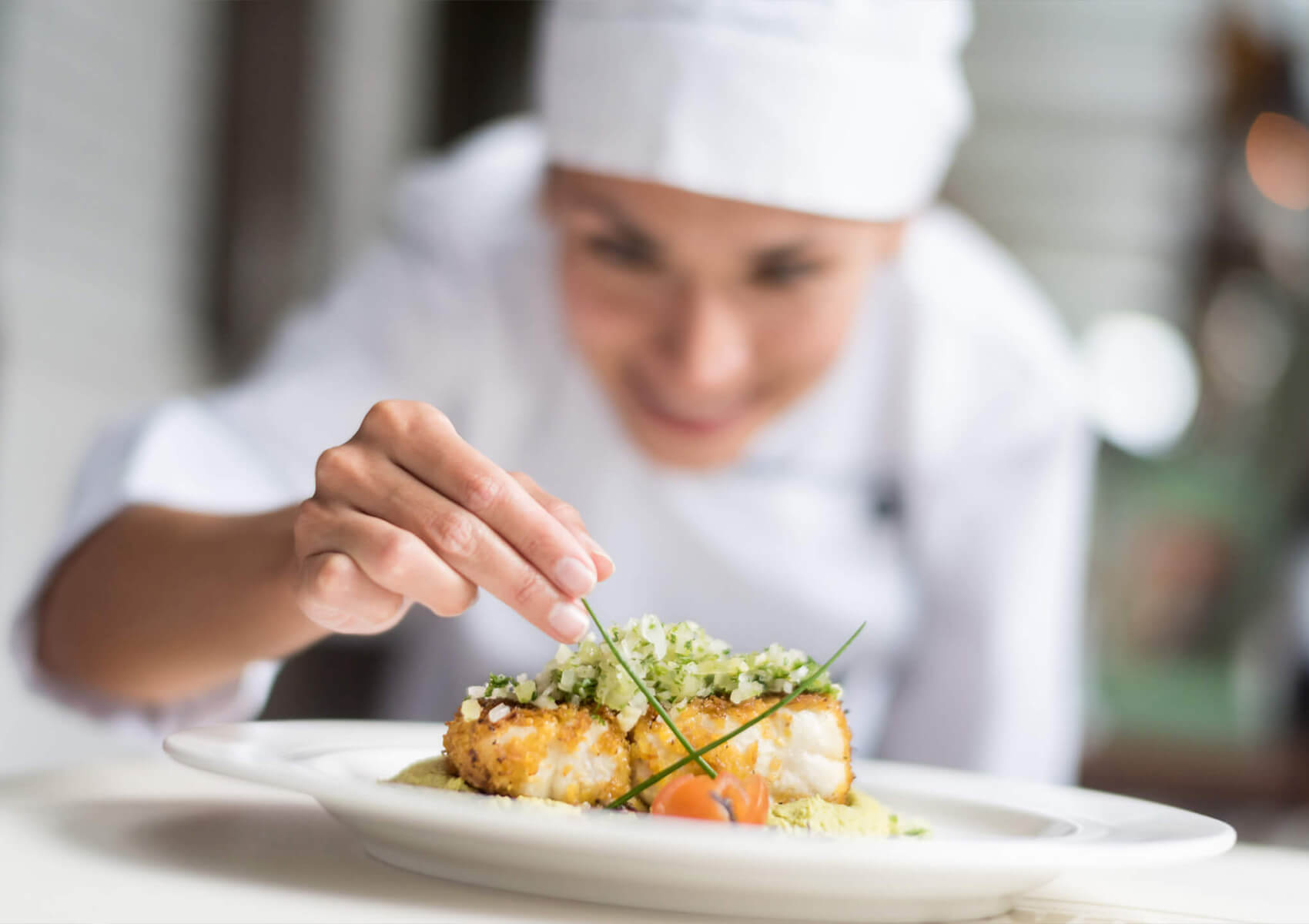 Chef plating an entree and adding garnish.