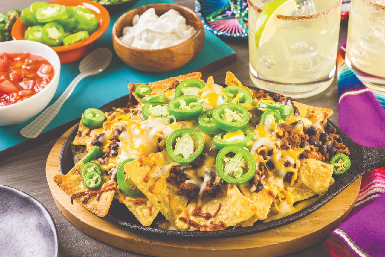 Plate of loaded nachos with dips and sides
