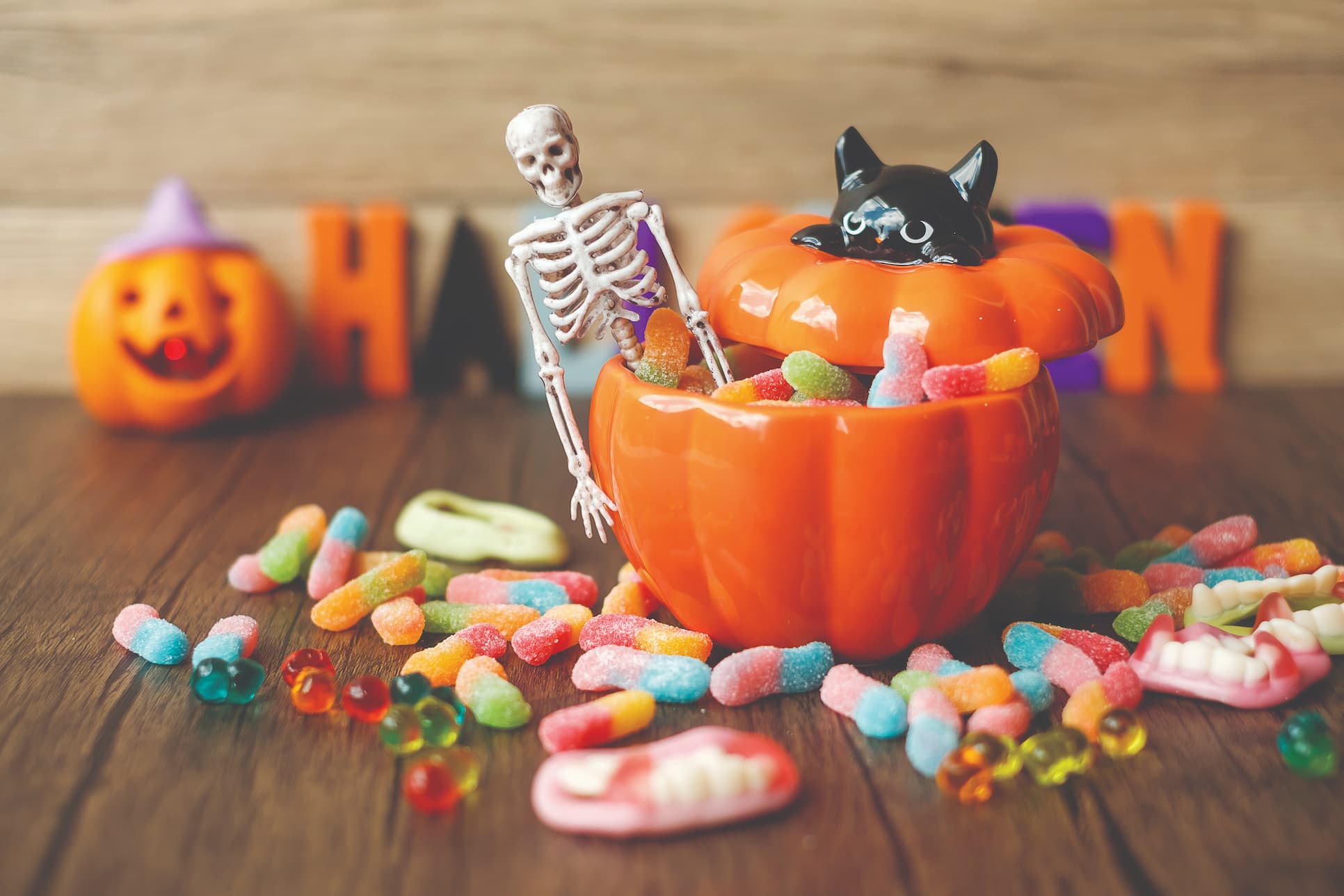 Pumpkin shaped bowl full of gummy worms and little halloween decor