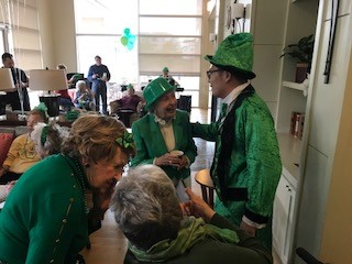 Residents in green attire celebrate St. Patricks Day in the common area of a multi-unit building.